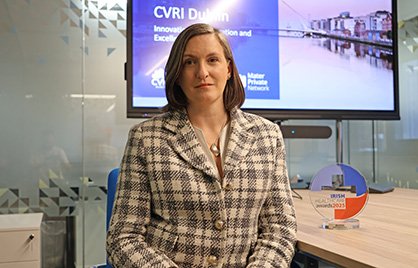 Amy Carswell sitting in the CVRI Dublin boardroom beside an Irish Healthcare Award
