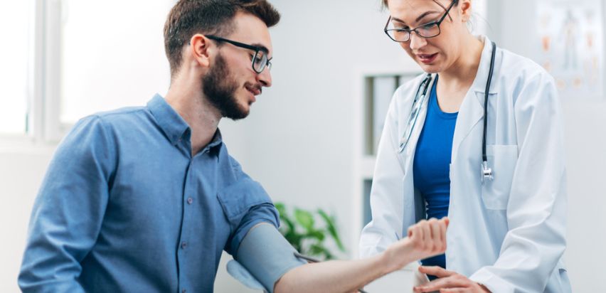 A man is having his blood pressure checked by a female doctor during a health screening.