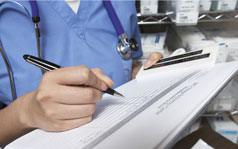 A close up of a medical professional writing on a paper form.