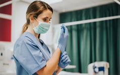 Why-choose-us-238x149 A female medical professional wearing a surgical mask and putting on gloves.