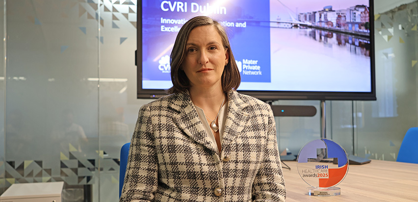 Amy Carswell sitting in the CVRI Dublin boardroom beside an Irish Healthcare Award