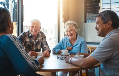A mature couple sitting on the table chatting with firends