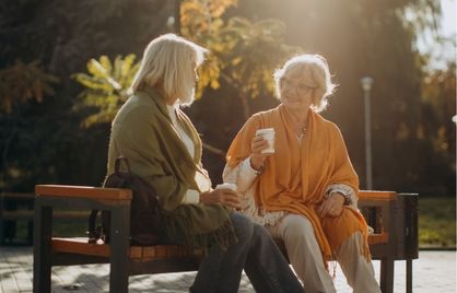 Two middle age women chatting on a park bench