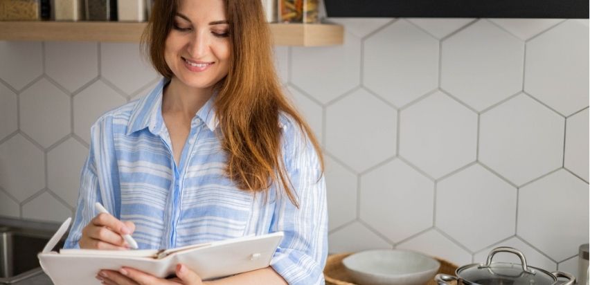 Women writing on her diary in the kitchen