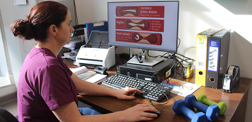 Irene social 3 - Article Image Irne Murphy is looking at a presentation on her computer screen. The presentation is in white and red. It has headings such as coronary artery disease, angina, and heart attack.