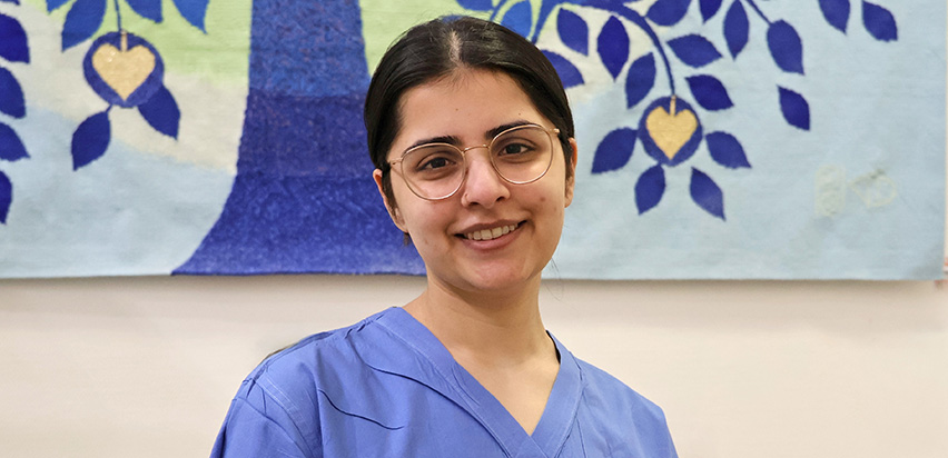 Mahreen Khosa is smiling as she stands in front of a colourful painting