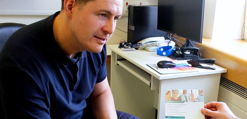 Sean Byrne showing the Strength & Balance Programme leaflet to a patient.