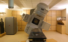 A radiotherapy machine in a hospital treatment room is rotating around a bed.