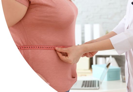 A female doctor measuring a female patient's waist circumference.