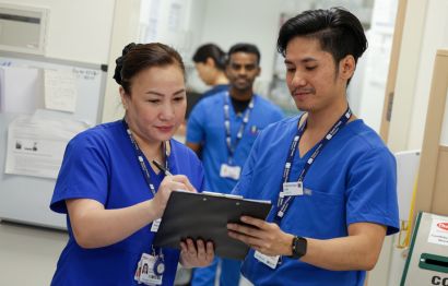 Two Mater Private nurses examining patient records on a clipboard in a hospital setting.