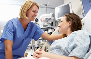 Nursing assisting a patient in a hospital bed